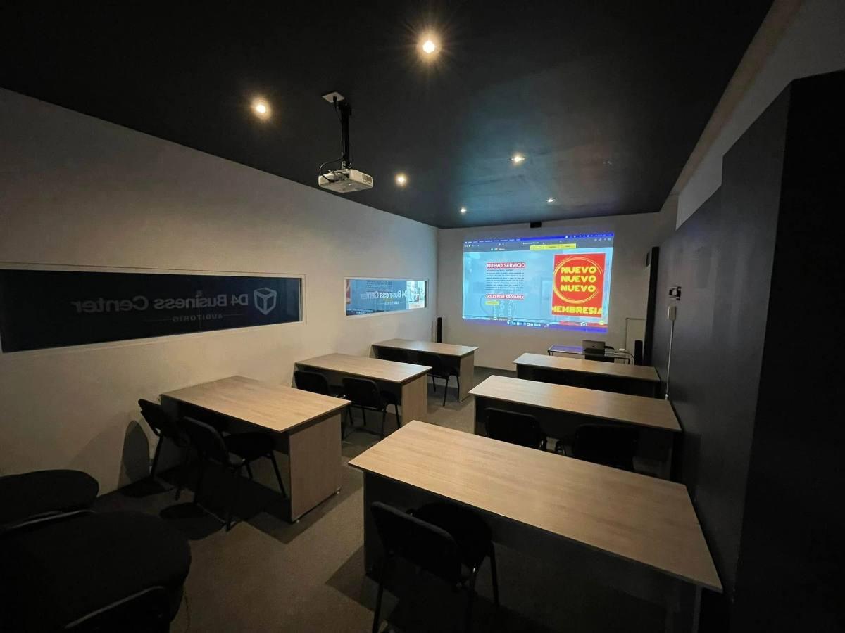 Auditorio de D4 con mesas en filas y proyector